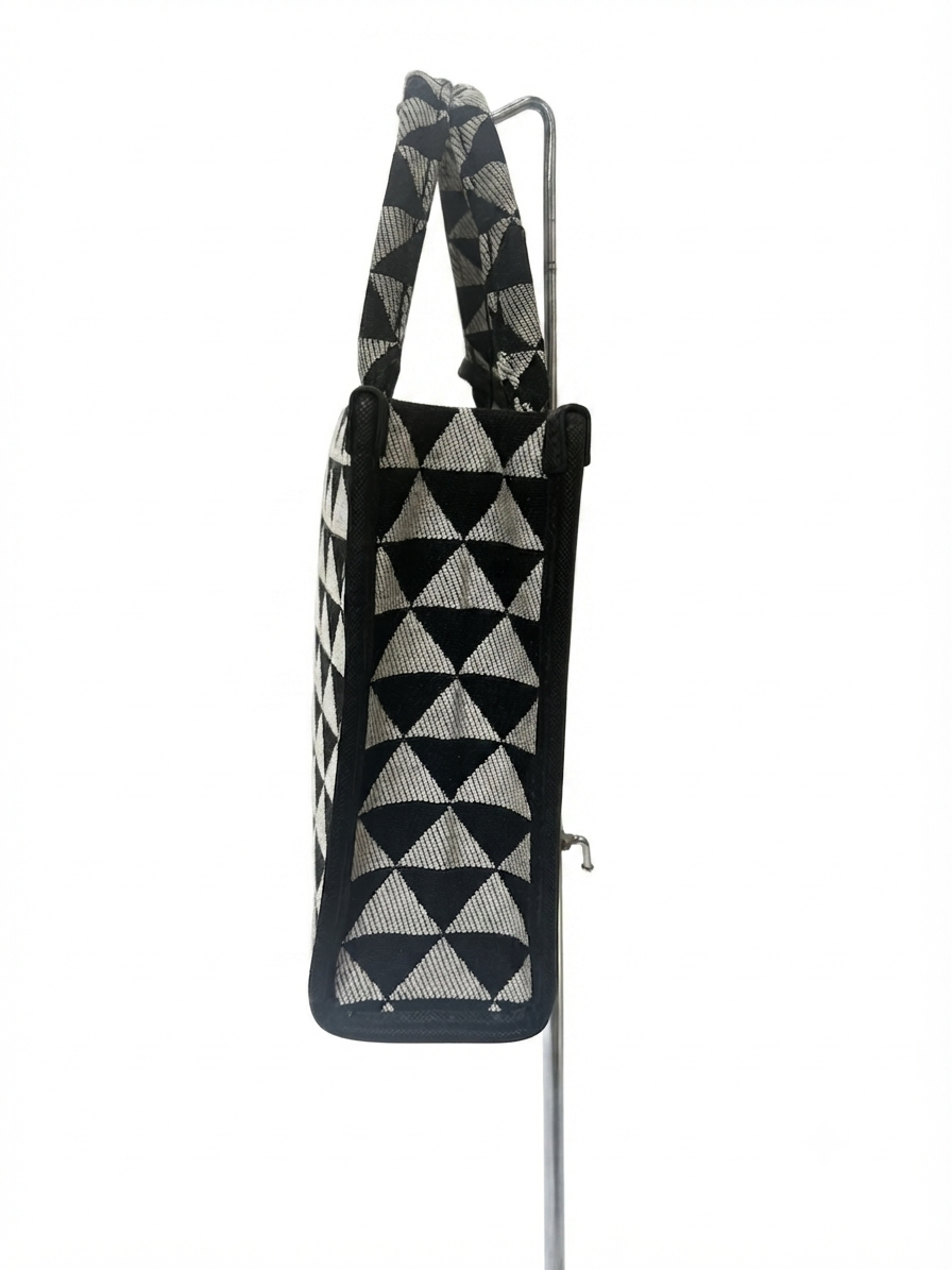 Prada Symbole Jacquard fabric handbag features a black and beige geometric pattern adorned with yellow and green embroidered floral motifs