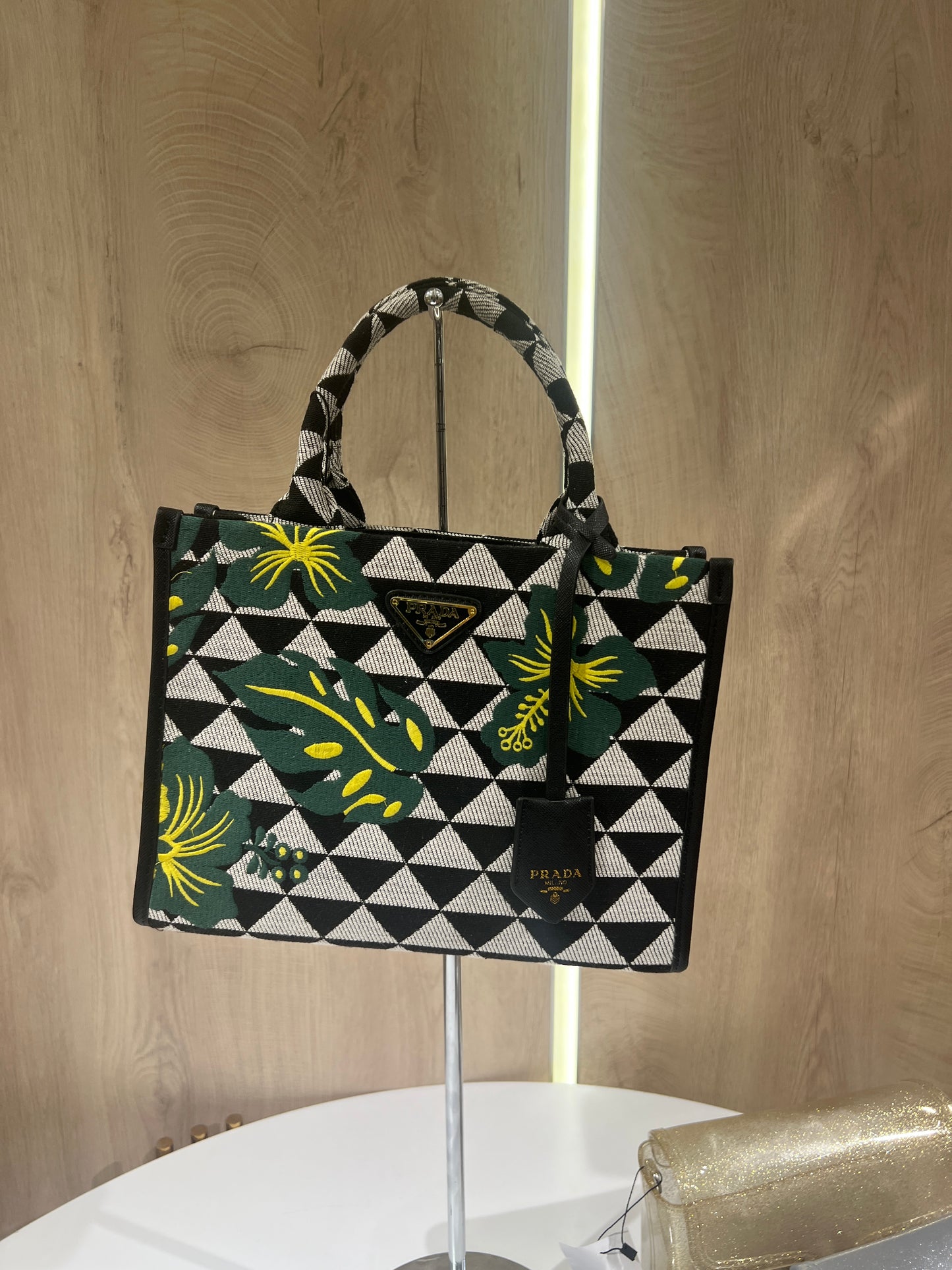 Prada Symbole Jacquard fabric handbag features a black and beige geometric pattern adorned with yellow and green embroidered floral motifs