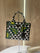 Prada Symbole Jacquard fabric handbag features a black and beige geometric pattern adorned with yellow and green embroidered floral motifs