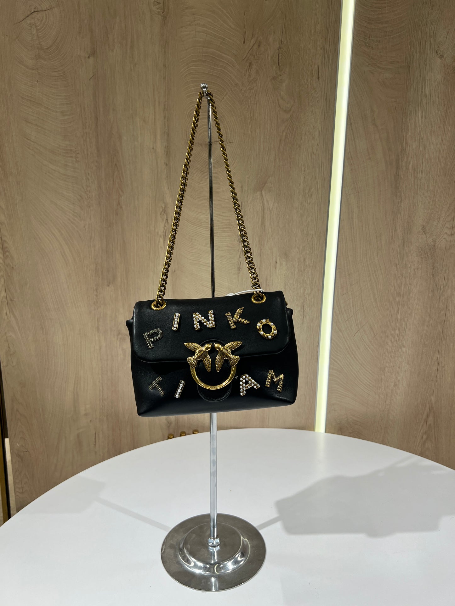 Black Pinko Mini Love Puff Logo handbag featuring prominent rhinestone lettering and a signature gold-toned bird buckle.